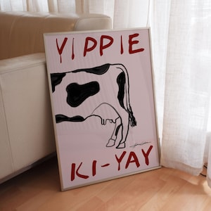 Dark pink poster that shows a painting of a half of a cow that says "Yippie Ki-Yay" in red painting