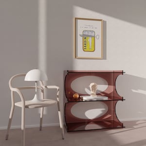 Chic Hand-drawn minimalist kitchen and bar cart print "Sardines" art print poster by KunstbyStephie. A white chair with a curved back and a white lamp with a dome shade. A brown shelf with two shelves and a white bust on the top shelf. A framed print with the words 'Sardines' and a picture of a sardine can with a knife on top of it.