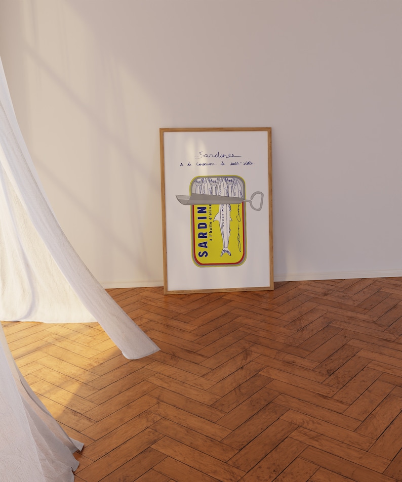 Chic Hand-drawn minimalist kitchen and bar cart print "Sardines" art print poster by KunstbyStephie. A framed print of a yellow sardine can with a silver can opener. The can is labeled 'SARDIN - A L'HUILE D'OLIVE' and has a drawing of a sardine inside. The text above the can reads 'Sardines a la conserve - le sel - sel - sel'.