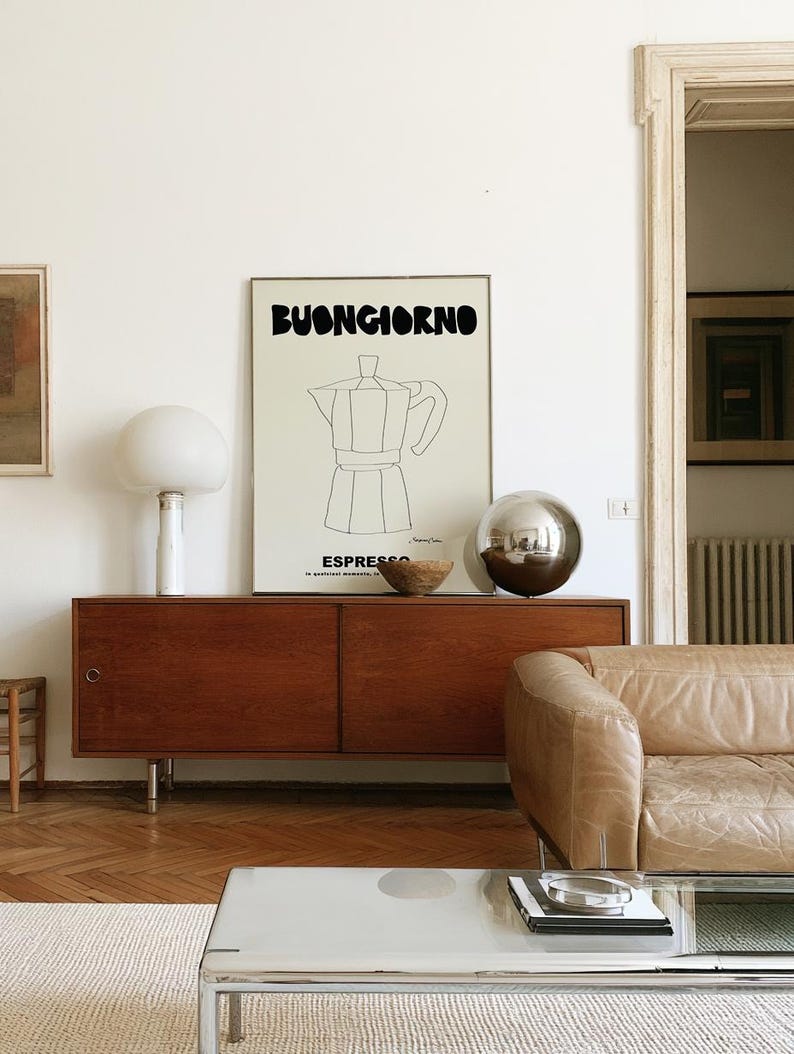 May include: A rectangular wall art print featuring the black text BUONGIORNO at the top and ESPRESSO at the bottom, with a central black line drawing of a moka pot coffee maker on a light cream background, framed in a thin metallic border.