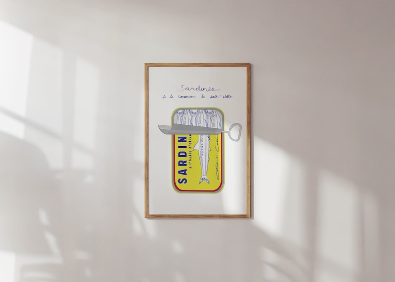 Chic Hand-drawn minimalist kitchen and bar cart print "Sardines" art print poster by KunstbyStephie. A framed print of a yellow sardine can with a silver can opener. The can is labeled 'SARDIN - A L'HUILE D'OLIVE' and has a blue and white illustration of sardines. The text above the can reads 'Sardines de la Conserverie de Dall-Vella'.