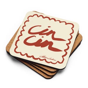 May include: A stack of four square coasters. The top coaster has a cream-colored background with a red scalloped border and the words "Cin Cin" in red script. The bottom three coasters are made of cork.
