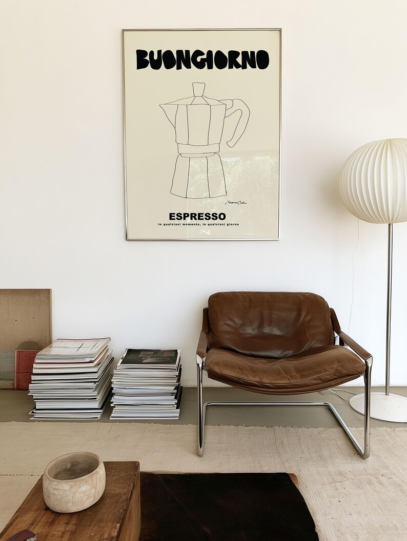 May include: A rectangular wall art print in a thin silver frame featuring a cream background with black text that reads BUONGIORNO and ESPRESSO, along with a black line drawing of a moka pot and the small signature of the artist at the bottom.