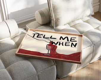 May include: A framed print with a white background and a black and red illustration of a wine bottle pouring wine into a glass. The text "TELL ME WHEN" is written in black above the illustration.