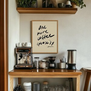 Puede incluir: Una estaci&oacute;n de caf&eacute; con un cartel enmarcado que dice "One more coffee (please) x". Incluye una m&aacute;quina de espresso de acero inoxidable, un molinillo de caf&eacute; y varios tazas y accesorios. Una estanter&iacute;a de madera arriba contiene plantas y objetos decorativos.