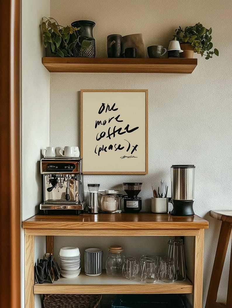 Puede incluir: Una estaci&oacute;n de caf&eacute; con un cartel enmarcado que dice "One more coffee (please) x". Incluye una m&aacute;quina de espresso de acero inoxidable, un molinillo de caf&eacute; y varios tazas y accesorios. Una estanter&iacute;a de madera arriba contiene plantas y objetos decorativos.