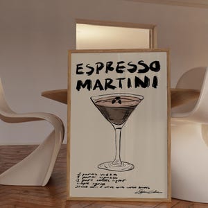 May include: A framed print with an Espresso Martini illustration. The artwork displays the words "ESPRESSO MARTINI" in bold, black lettering. The recipe is listed below the cocktail image: vodka, espresso, coffee liqueur, and simple syrup.