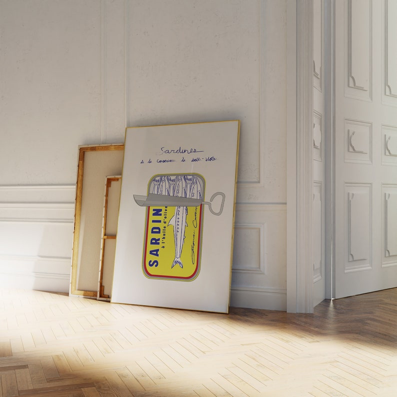 Chic Hand-drawn minimalist kitchen and bar cart print "Sardines" art print poster by KunstbyStephie. A white framed poster with a yellow and blue sardine can illustration. The can is open and the sardines are visible. The text on the poster reads 'Sardines a l'huile d'olive et sel - 1/2 kilo'.