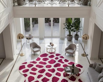 May include: An interior shot of a luxurious living room with a large, patterned rug in shades of white and burgundy. The room features a balcony, large windows, and a crystal chandelier. Furnishings include sofas, chairs, and side tables.
