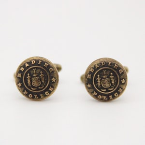 May include: A pair of gold cufflinks with a black enamel design featuring the Reading Police crest and the words "Reading Police".