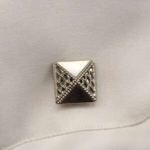 May include: Silver cufflinks with a white mother of pearl inlay and a geometric design.
