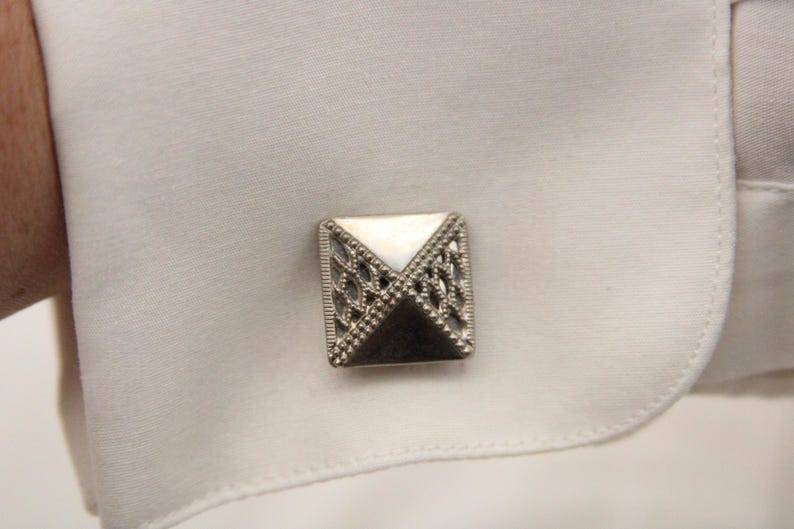 May include: Silver cufflinks with a white mother of pearl inlay and a geometric design.