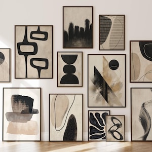 May include: A gallery wall collection of twelve framed art prints featuring abstract compositions in black, beige, and cream. The prints display various geometric shapes, organic forms, brushstrokes, and line art, all enclosed in dark brown frames.