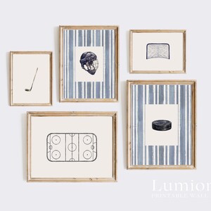 May include: A set of five framed prints featuring hockey-themed illustrations. The prints include a hockey stick, a helmet, a net, a hockey puck, and a hockey rink. The frames have a light wood finish and are arranged on a white wall.
