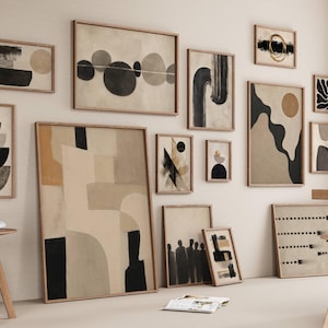 May include: A gallery wall arrangement featuring multiple framed art prints in neutral tones of beige, cream, black, and brown. The collection includes various abstract compositions, geometric shapes, and organic forms displayed in light wood frames.