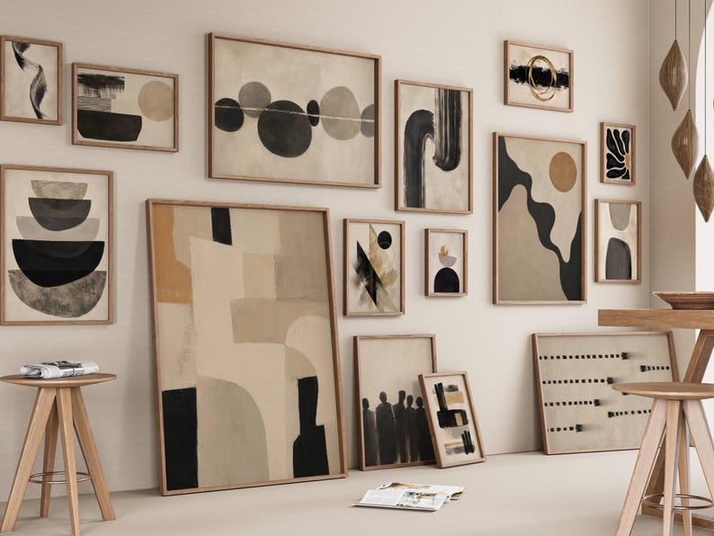 May include: A gallery wall arrangement featuring multiple framed art prints in neutral tones of beige, cream, black, and brown. The collection includes various abstract compositions, geometric shapes, and organic forms displayed in light wood frames.