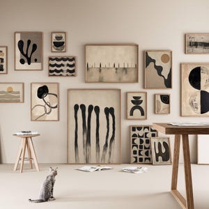 May include: A gallery wall featuring a collection of framed abstract art prints in neutral tones of beige, black, and white. The artwork displays various geometric shapes, organic forms, and linear patterns, all housed in light-colored wooden frames.