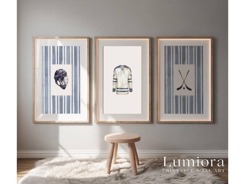 May include: Three framed wall art prints featuring hockey-themed illustrations. The prints include a hockey helmet, a jersey, and crossed hockey sticks. Each print has a blue and white striped background and a wooden frame.