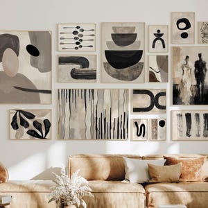 May include: A gallery wall arrangement featuring seventeen framed art prints in shades of black, white, beige, and gray. The collection includes abstract shapes, organic forms, linear patterns, and a figurative silhouette, all displayed in light wood frames.