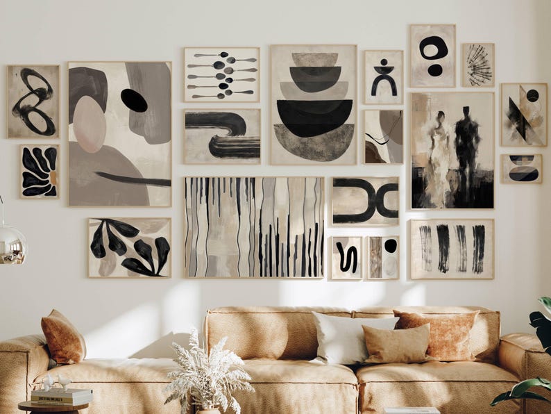May include: A gallery wall arrangement featuring seventeen framed art prints in shades of black, white, beige, and gray. The collection includes abstract shapes, organic forms, linear patterns, and a figurative silhouette, all displayed in light wood frames.