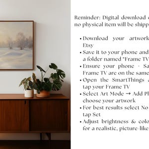 May include: A framed landscape painting depicting a snowy field and trees under a soft, overcast sky. The artwork is displayed above a mid-century modern wooden cabinet with potted plants. The image includes instructions for downloading the artwork.