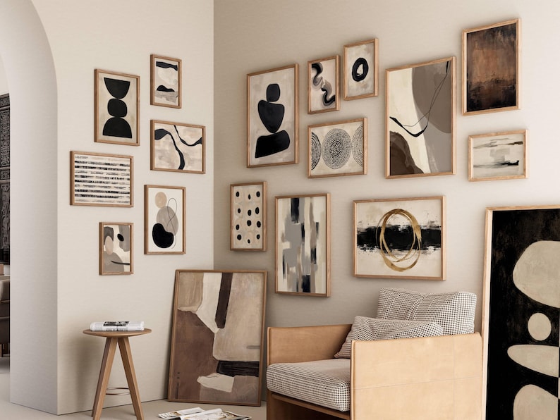 May include: A gallery wall arrangement featuring numerous framed abstract art prints in various sizes. The collection includes black, white, beige, and gold tones with geometric shapes, lines, and organic forms displayed on a light-colored wall.