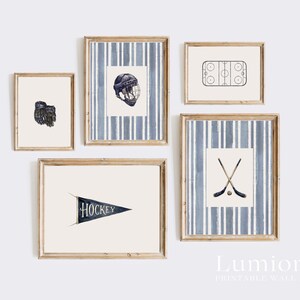 May include: A set of five framed wall art prints with a hockey theme. The prints feature illustrations of a hockey glove, helmet, rink, crossed hockey sticks and a pennant with the word "HOCKEY". The frames are a light wood color.