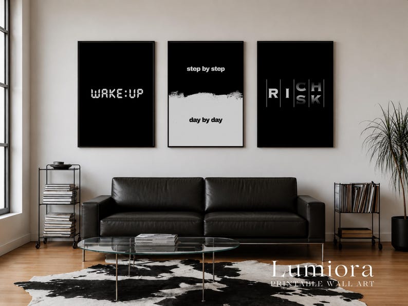 May include: Three rectangular wall art prints in black frames. The left print has a black background with the white text WAKE:UP. The center print is split horizontally with step by step on black and day by day on white. The right print says RICH RISK.