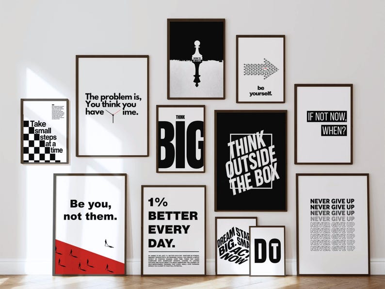 May include: A gallery wall collection of twelve framed posters featuring black and white motivational typography and graphic designs, including phrases like Think Outside The Box, Be You, Not Them, and Never Give Up, arranged in a grid layout.