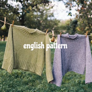 Könnte beinhalten: Zwei Strickpullover, einer olivgrün und einer grau, hängen an einer Wäscheleine mit Holzklammern. Der Text "english pattern" ist auf der Vorderseite des grünen Pullovers zu sehen. Der Hintergrund zeigt eine grüne Wiese und Bäume.