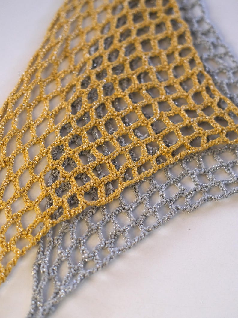 Pode incluir: Close-up de dois tecidos de rede de croch&ecirc;. Um &eacute; dourado, o outro prateado. A trama aberta da rede cria uma textura delicada e arejada. Os tecidos s&atilde;o provavelmente usados para fins decorativos ou como acess&oacute;rios de moda.