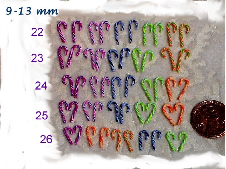 May include: Assortment of candy cane shaped ornaments in various colors, including purple, pink, green, orange, and blue. The ornaments are arranged in rows, with each row labeled with a number from 22 to 26. The text "9-13 mm" is visible at the top of the image.