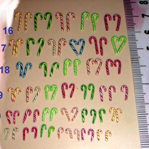 May include: A ruler with measurements in millimeters from 5 to 13, with a row of 11 candy canes in each row, from 16 to 21, with different colors and patterns, including red, white, green, yellow, and blue.
