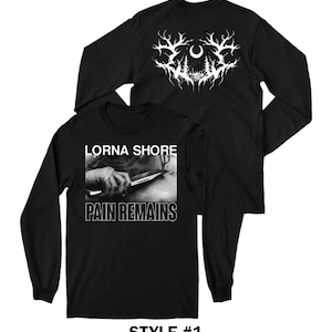 May include: Black long-sleeve shirt featuring the text "LORNA SHORE" above a black and white image of a hand holding a knife, with the words "PAIN REMAINS" below. The back of the shirt has a white graphic of trees and branches.