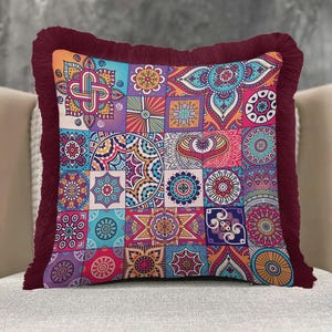 May include: Square decorative pillow with a patchwork design featuring colorful geometric and floral patterns in shades of blue, orange, purple, and pink. The pillow has a burgundy fringe border.