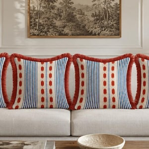 May include: Four square throw pillows featuring a vertical pattern of blue stripes and a central column of red dots on an off-white background. Each pillow is finished with a textured red fringe trim along all four edges, creating a uniform look.