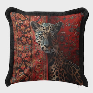 May include: Decorative throw pillow featuring a leopard with a spotted coat, set against a red and black patterned background. The pillow has a black fringe border, adding a touch of elegance to the design.