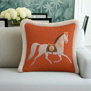Create a sanctuary of style in your bedroom. This Orange Horse Pillow is the perfect decorative accent for your bed set. Its warm tones invite relaxation, while the classical motif adds a sense of calm elegance. The soft fringes are gentle to the touch, making it as comfortable as it is beautiful. Pair it with neutral linens for a stunning look.