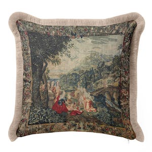 Op de afbeelding: Decoratief kussen met een tapijtdesign met een klassieke landschapsbeeld met figuren in rode en crèmekleurige kleding. Het kussen heeft een beige franjeborduur en een ritssluiting.