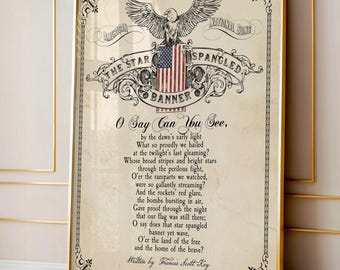 May include: A framed print featuring the lyrics to The Star-Spangled Banner, written by Francis Scott Key. The design includes a central illustration of an eagle perched atop an American flag, surrounded by ornate black scrollwork on a cream background.