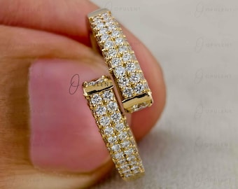 May include: A gold hoop earring featuring two parallel rows of small, round, clear pavé-set stones. The earring has a hinged design and a polished gold finish, showcasing a continuous sparkling surface across the front of the curved band.
