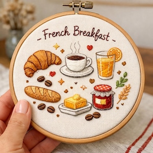 Puede incluir: Arte de aro bordado con una escena de desayuno francés. Incluye un cruasán, café, zumo, pan, mantequilla y mermelada. El texto "- French Breakfast -" está bordado encima de los elementos del desayuno. El bordado está en un aro de madera.