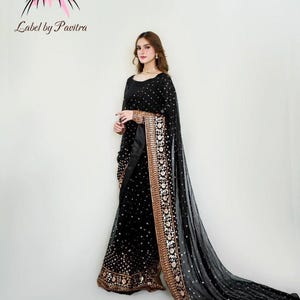 May include: A black formal dress with gold detailing and a matching long scarf. The dress has a round neckline and long sleeves. The scarf and dress are decorated with small, sparkling elements. The brand name "Label by Pavitra" is visible.