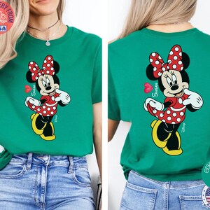 May include: A teal green t-shirt with a Minnie Mouse design on the front and back. Minnie is depicted in a red polka dot dress and bow, with yellow shoes. The name "Susan" is written on the shirt.