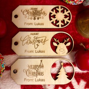 May include: Three wooden Christmas gift tags with laser-cut designs. Each tag has "Merry Christmas" and "From: Lukas" engraved. One tag features a snowflake, another a reindeer, and the last a Christmas tree.