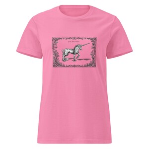 Peut inclure: Un t-shirt rose vif à manches courtes avec une impression graphique rectangulaire en noir et blanc sur la poitrine. L'imprimé représente une illustration détaillée au trait d'une licorne dans une bordure florale avec le texte "of the UNICORN".