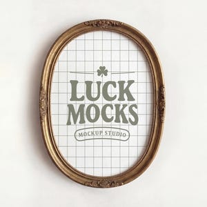 Puede incluir: Un marco de fotos ovalado, de color dorado, con detalles ornamentados. El marco rodea un fondo blanco con un patrón de cuadrícula y el texto "LUCK MOCKS" en una fuente verde-gris, con "MOCKUP STUDIO" debajo.