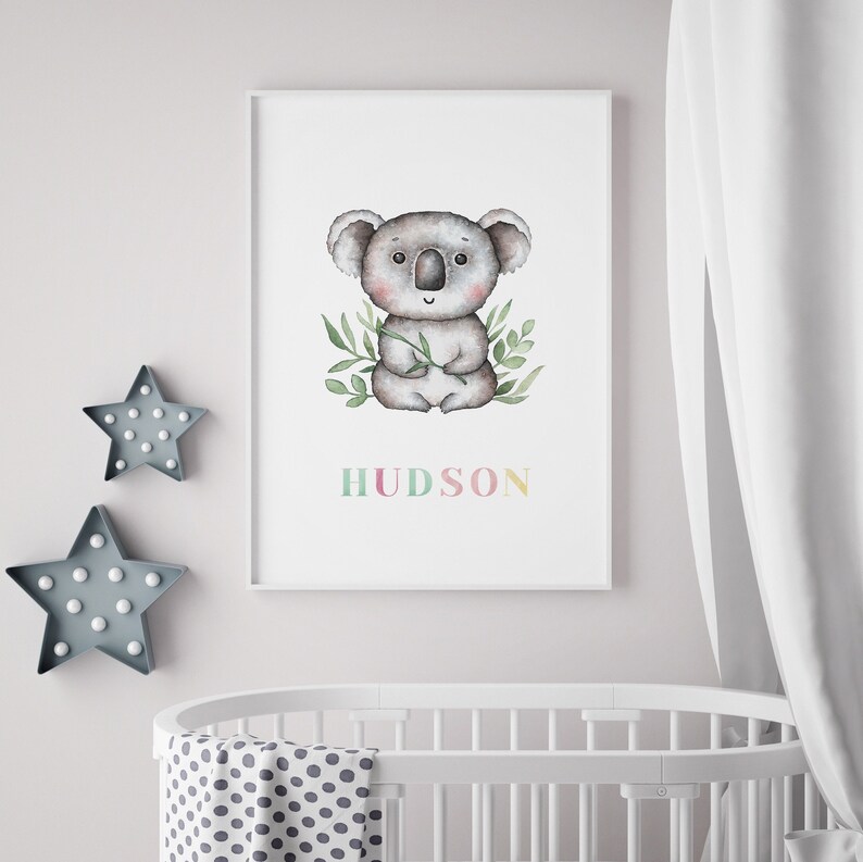 May include: A watercolour illustration of a koala holding a eucalyptus branch. The koala is sitting on a white background with green leaves surrounding it. The name "HUDSON" is written below the koala in colourful letters.