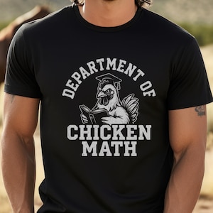 May include: Black t-shirt with the text "DEPARTMENT OF CHICKEN MATH" in white. The graphic features a chicken wearing a graduation cap and holding a book. The person in the image is wearing a black hat and black pants.