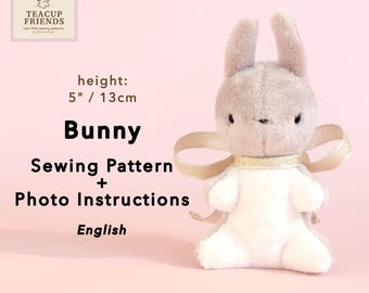 May include: A plush bunny sewing pattern with photo instructions. The bunny is light gray and white, with a gold ribbon around its neck. The bunny is 5 inches (13 cm) tall. The text "Bunny Sewing Pattern + Photo Instructions English" is visible.
